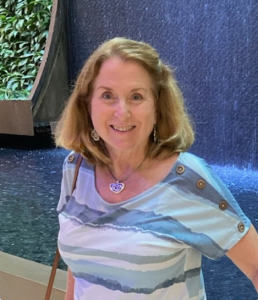 A woman, smiling wearing a white and blue tshirt
