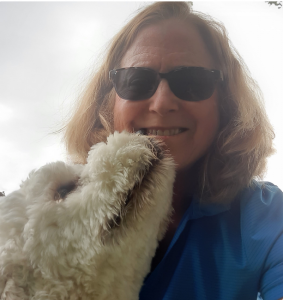 A woman with a puppy smiling with a clear sky